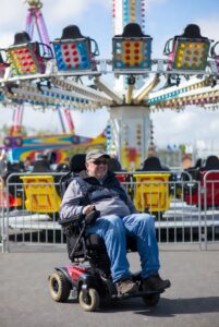 An older man in a mobility scooter at an amusement park
