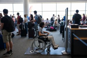 A wheelchair user waits in a crowded airport lobby